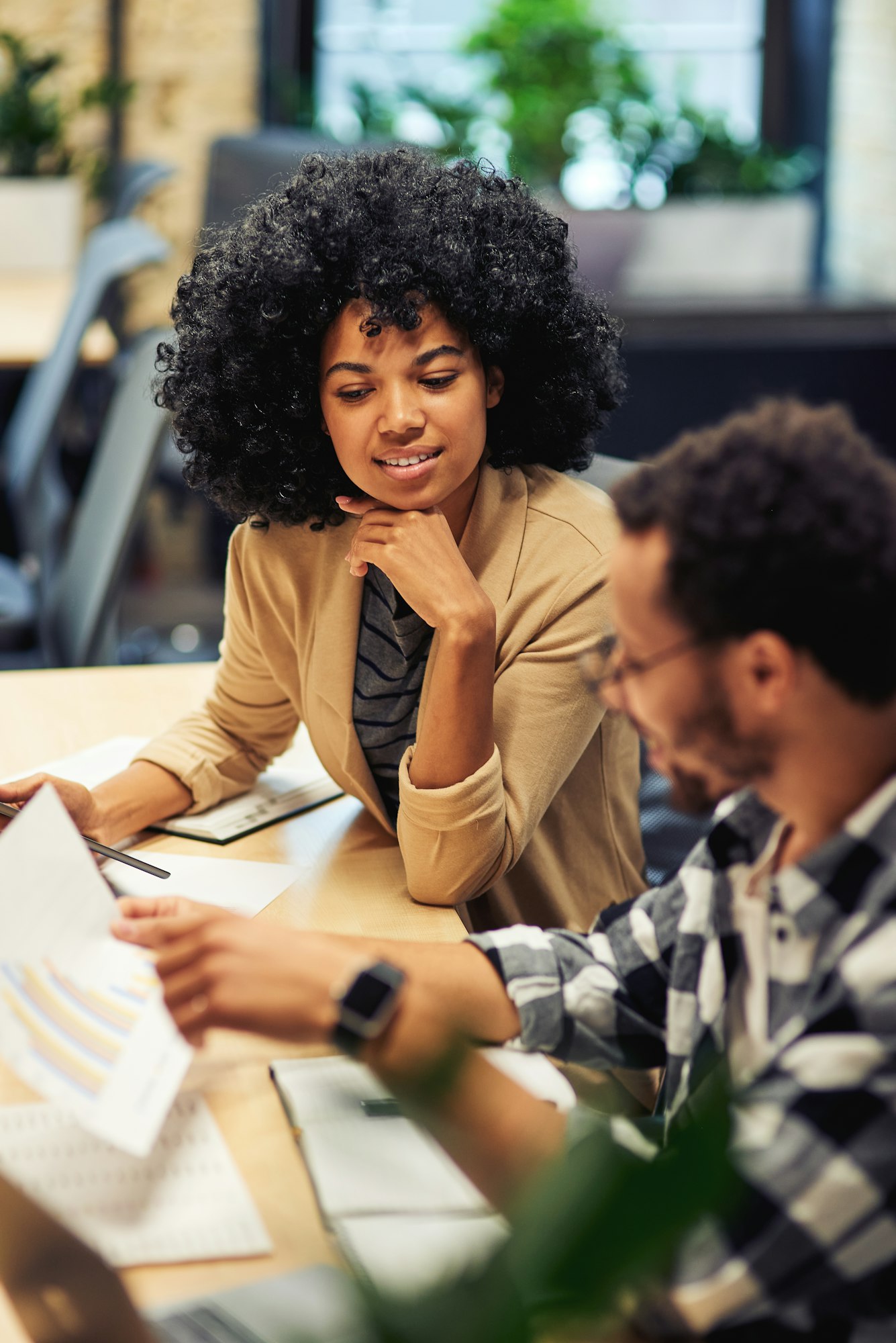 Two young diverse coworkers analyzing sales report while working together in the office